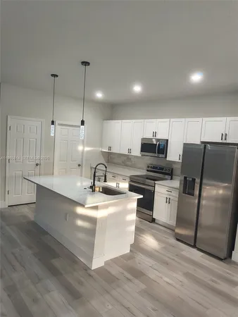 a kitchen with stainless steel appliances kitchen island granite countertop a sink a stove top oven a counter space and cabinets