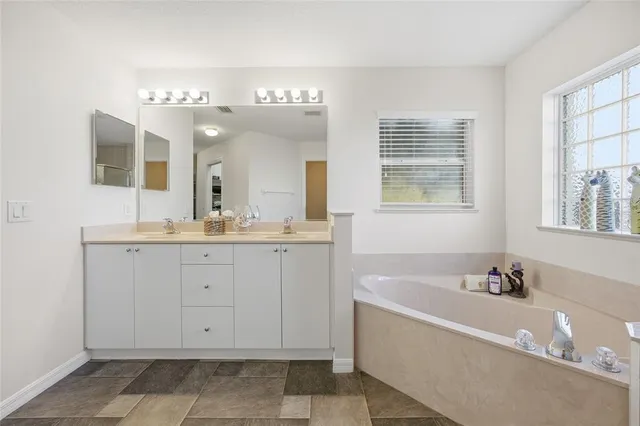 a spacious bathroom with a tub sink and mirror