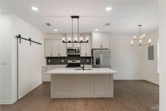 a view of a kitchen with a sink stainless steel appliances and chandelier