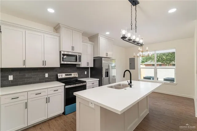 a kitchen with stainless steel appliances a sink a stove a microwave a center island and cabinets