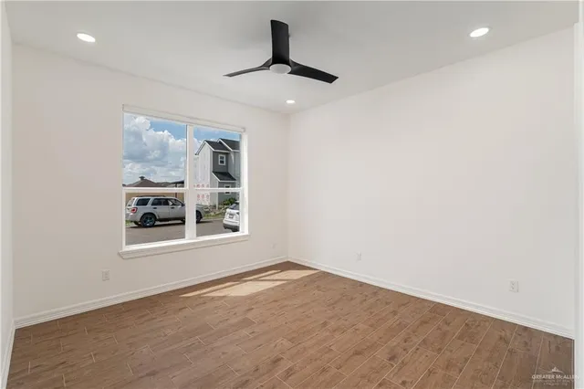a view of an empty room with a window and wooden floor