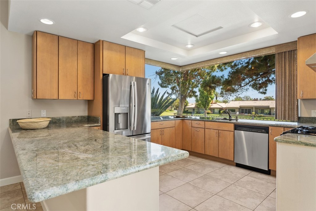 51 Pebble Beach Drive Rancho Mirage, CA 92270 - Photo 4 of 10 a kitchen with stainless steel appliances granite countertop a refrigerator a stove and a sink with large window