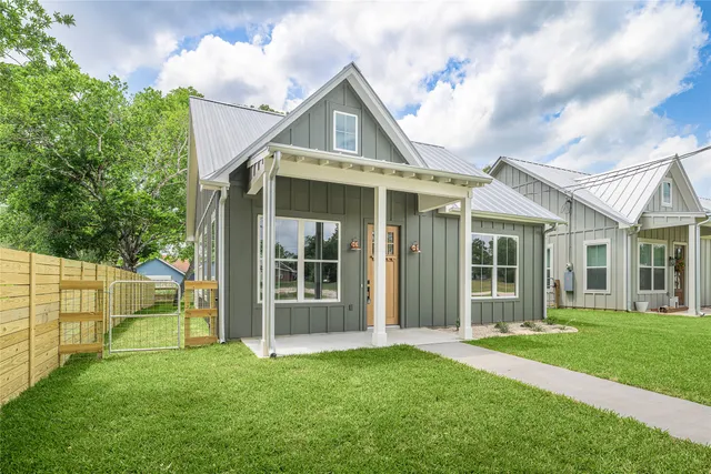 a view of a white house with a big yard and large trees