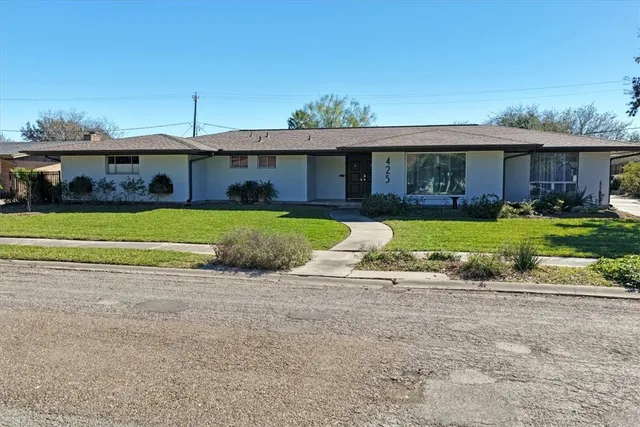a view of a house with a yard and a large tree