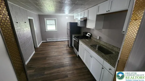 a kitchen with granite countertop a refrigerator a sink a stove and cabinets
