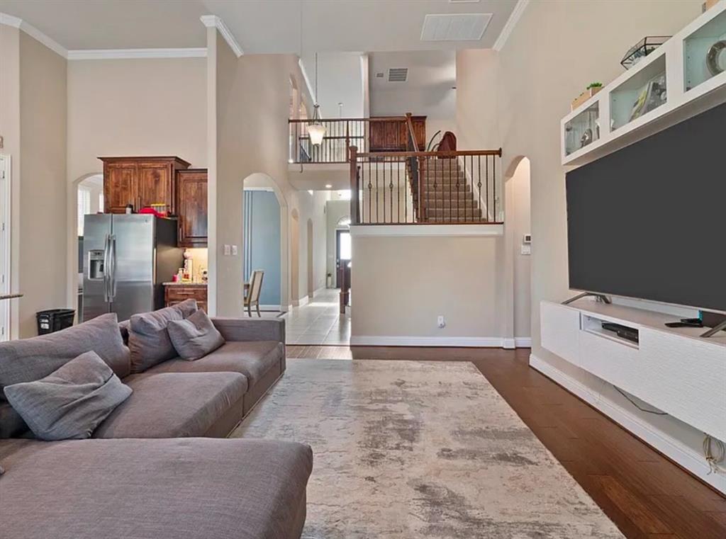 800 Gray Hawk Lane Euless, TX 76039 - Photo 2 of 8 Living room featuring crown molding, arched walkways, dark wood-style flooring, and a high ceiling