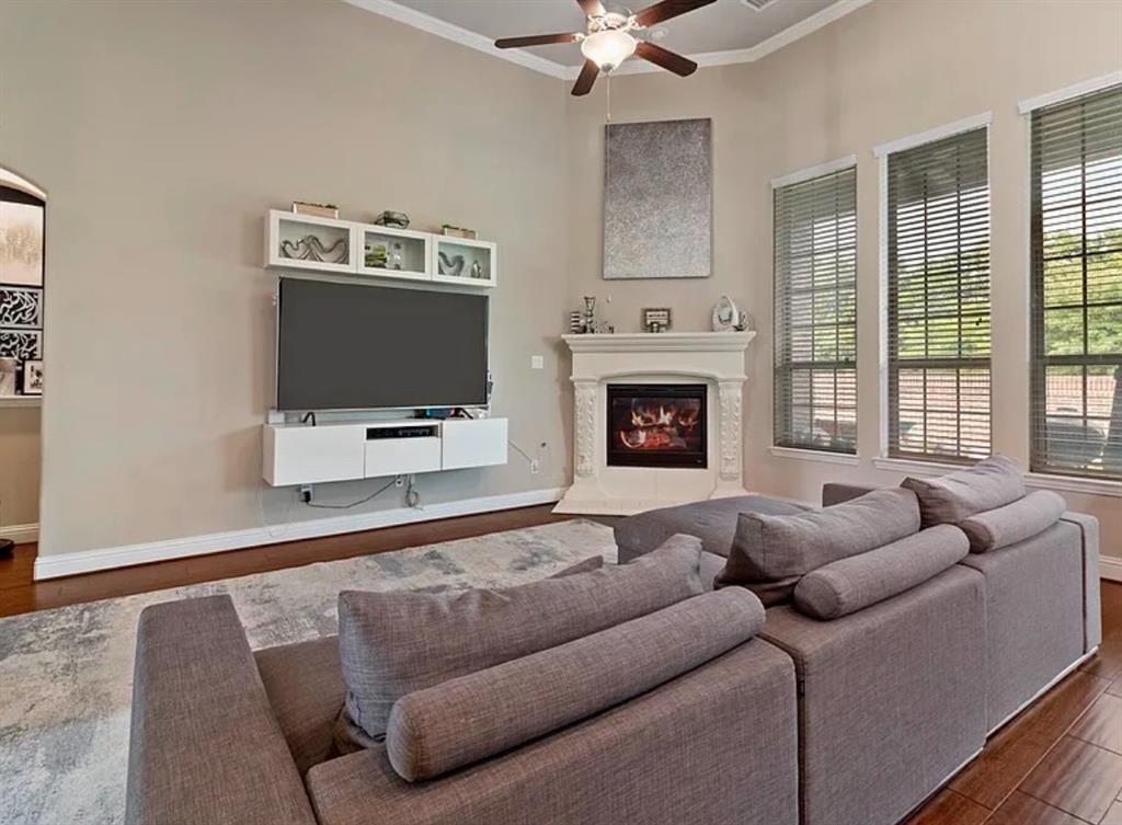 800 Gray Hawk Lane Euless, TX 76039 - Photo 4 of 8 Living room with wood finished floors, crown molding, a glass covered fireplace, and a ceiling fan