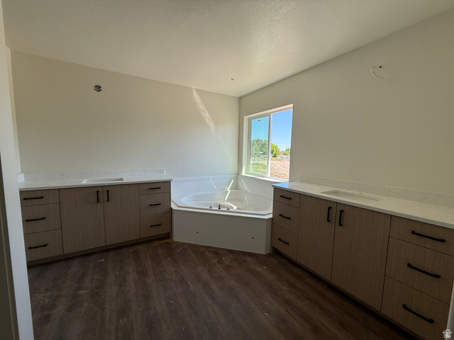 3308 South 1000 West Logan, UT 84321 - Photo 9 of 14 Spacious bathroom featuring a corner soaking tub, dual vanities with quartz countertops, wood-finish flooring, and a large window