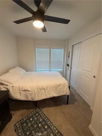 a large bed sitting in a bedroom next to a window and a chandelier