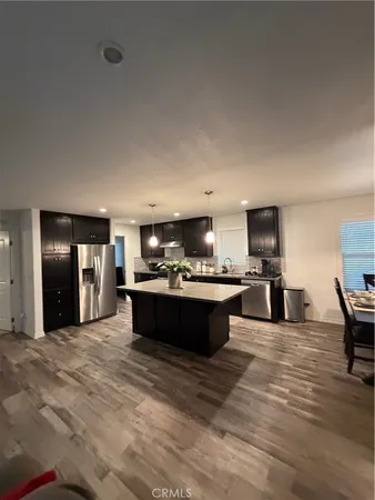 a large room with kitchen island stainless steel appliances wooden floors and view living room