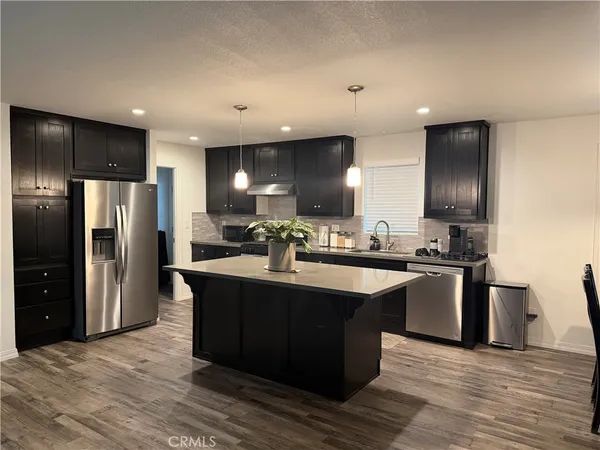 a kitchen with stainless steel appliances granite countertop a refrigerator a sink dishwasher a stove and a refrigerator