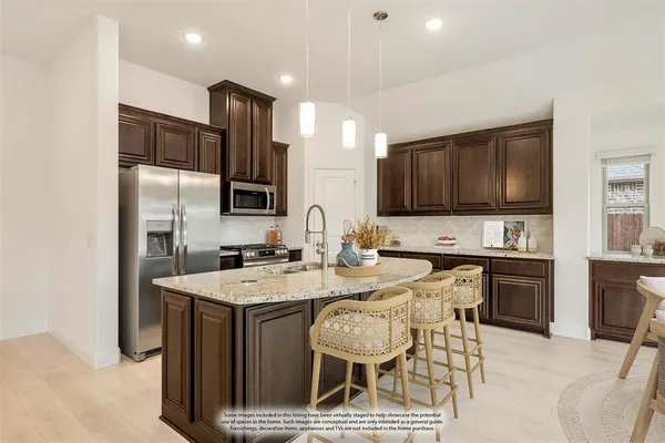 a kitchen with stainless steel appliances granite countertop a sink a stove a refrigerator cabinets and a dining table