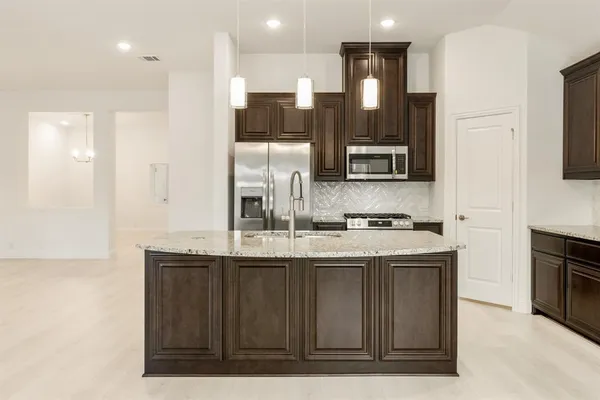 a kitchen with stainless steel appliances granite countertop a sink a stove and a refrigerator