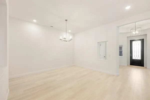an empty room with chandelier fan and windows