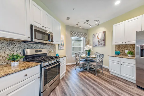 a kitchen with stainless steel appliances a stove a sink a microwave cabinets and a dining table