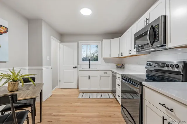 a kitchen with stainless steel appliances a stove a sink cabinets and a dining table