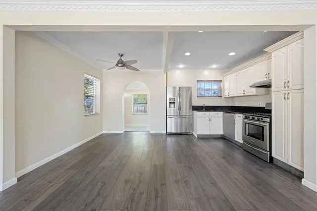 an empty room with wooden floor chandelier fan and windows