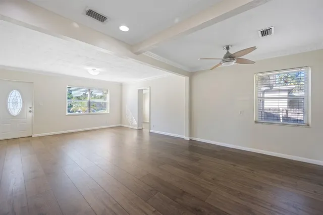 a view of an empty room with wooden floor and a window
