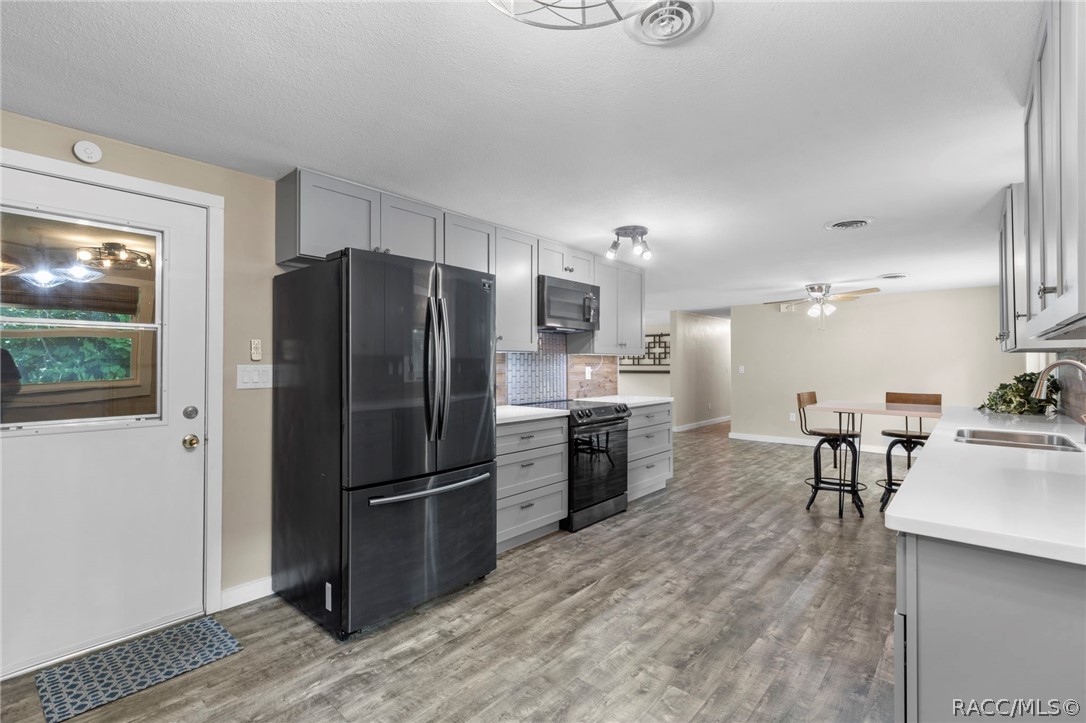 107 Allen Avenue Inglis, FL 34449 - Photo 10 of 36 a kitchen with a refrigerator a stove and a dining table with wooden floor