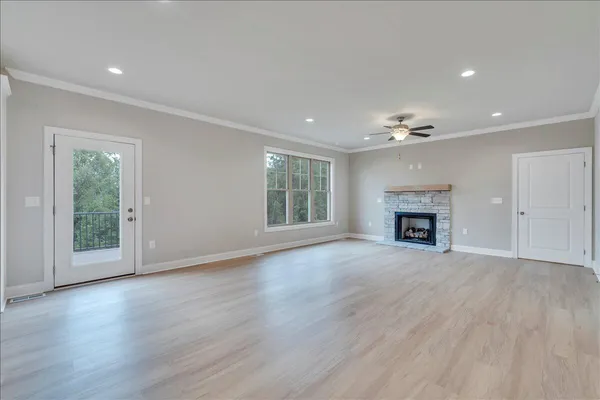 an empty room with wooden floor fireplace and windows