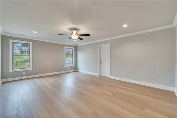 a view of an empty room with a window and wooden floor