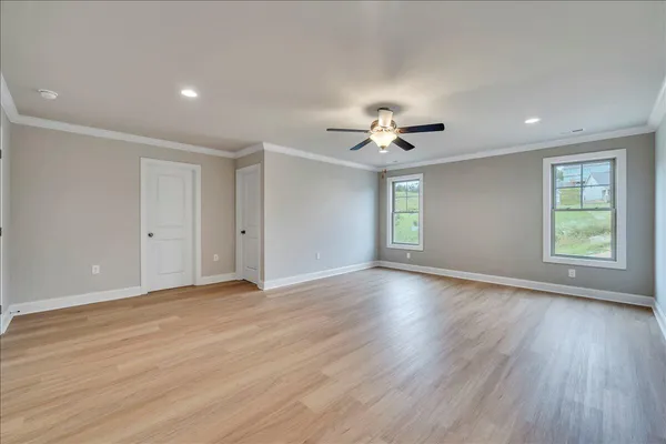 a view of an empty room with a window and wooden floor
