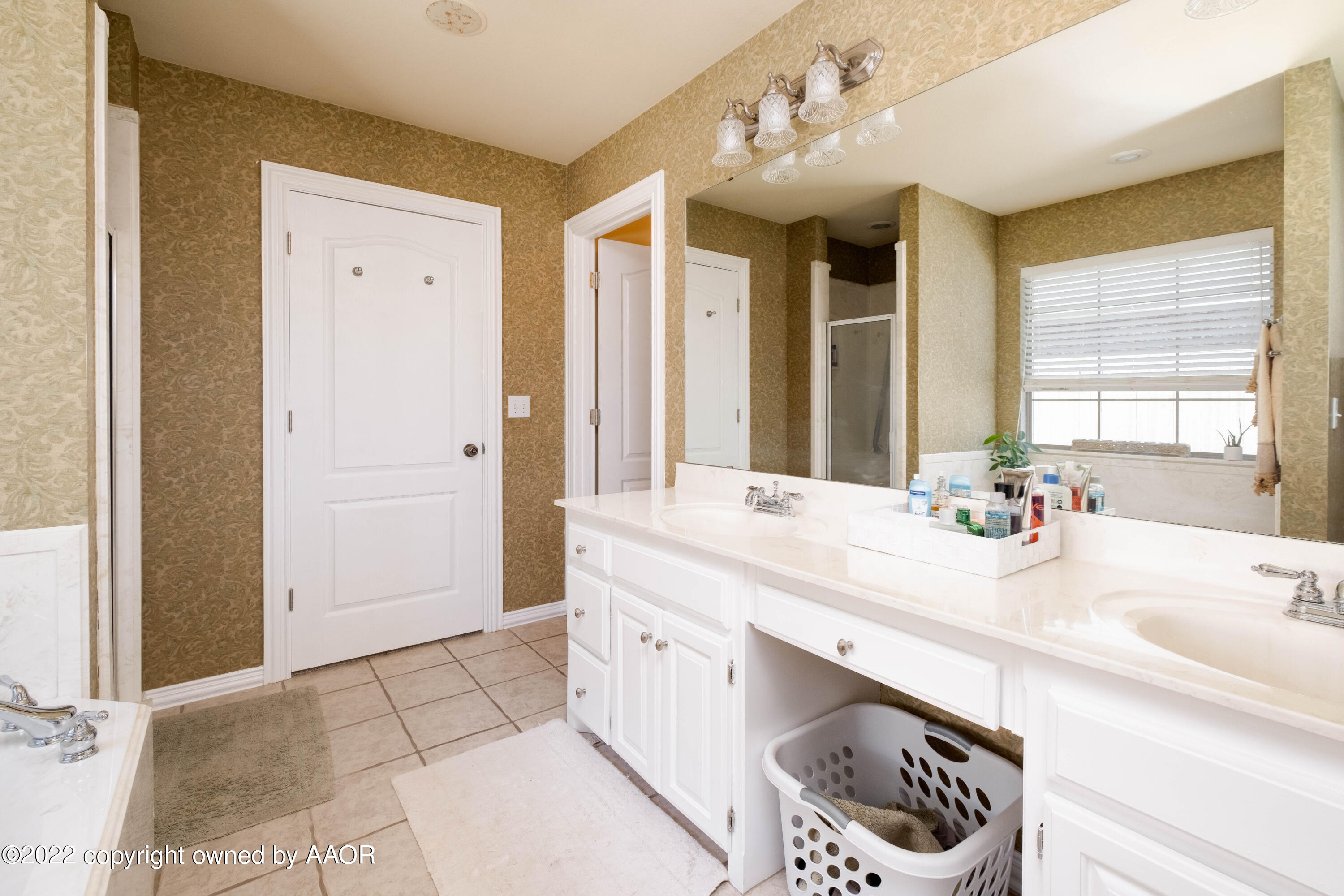 6607 Rally Road Amarillo, TX 79119 - Photo 21 of 34 a bathroom with a sink a mirror and a bathtub next to a window