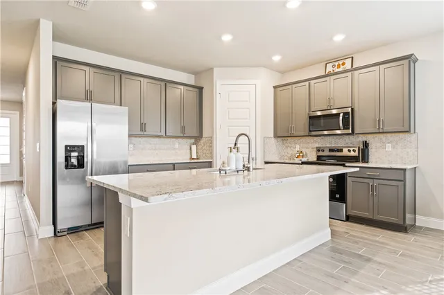 a kitchen with stainless steel appliances granite countertop a stove a sink and a refrigerator