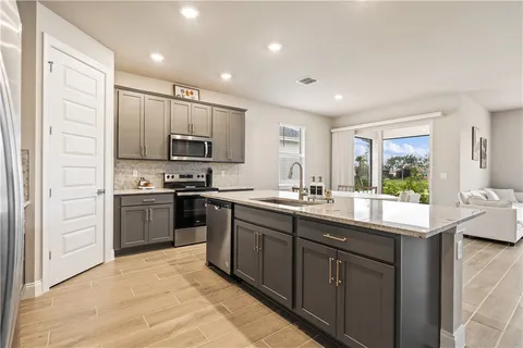 a kitchen with kitchen island granite countertop a sink stainless steel appliances and cabinets