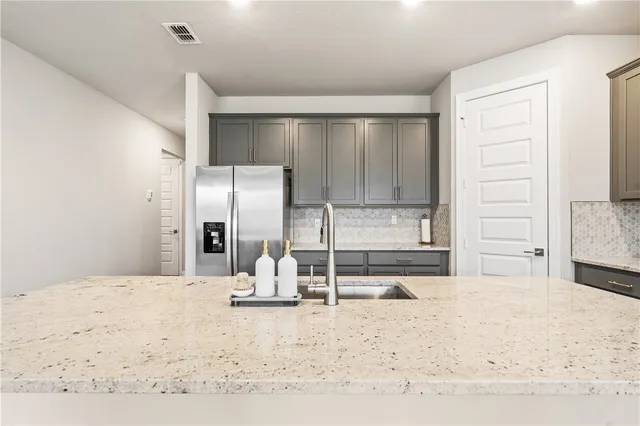 a kitchen with a refrigerator sink and cabinets