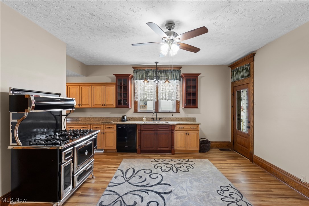 1011 Parriott Avenue Moundsville, WV 26041 - Photo 10 of 44 Kitchen with glass insert cabinets, light wood finished floors, black dishwasher, hanging light fixtures, and a textured ceiling
