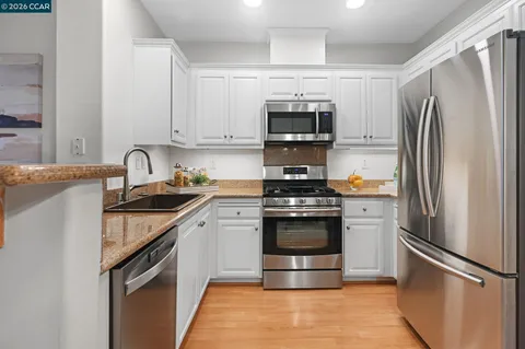 a kitchen with stainless steel appliances granite countertop grey cabinets a stove a sink and dishwasher