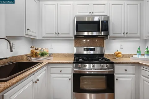 a kitchen with granite countertop a refrigerator stove and microwave