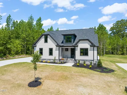 a front view of house with yard and trees in the background