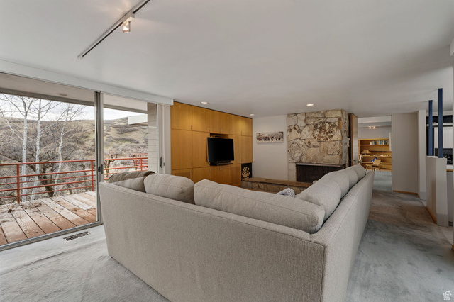 1856 Fort Canyon Road Alpine, UT 84004 - Photo 42 of 49 Spacious living area featuring a stone fireplace, wood-finish wall paneling with built-in media, track lighting, and sliding glass doors opening to an outdoor deck
