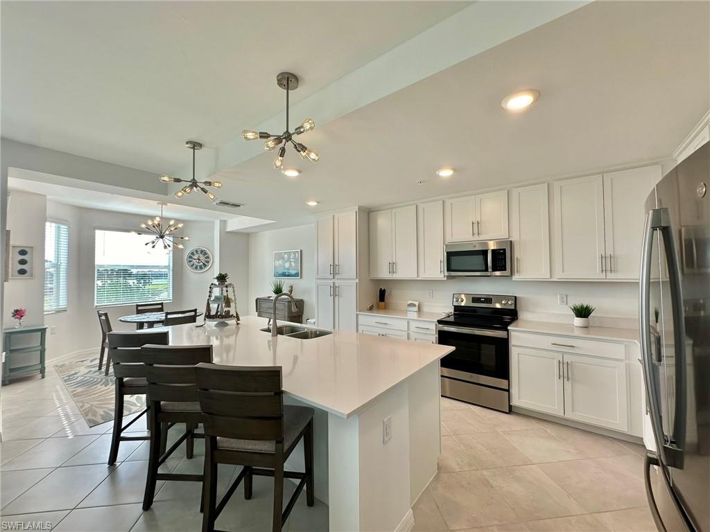 43997 Boardwalk Loop, Unit 1822 Babcock Ranch, FL 33982 - Photo 14 of 47 Kitchen featuring an island with sink, white cabinets, pendant lighting, and appliances with stainless steel finishes.