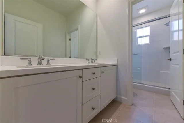 a en suite bathroom with a double vanity sink a mirror and a shower