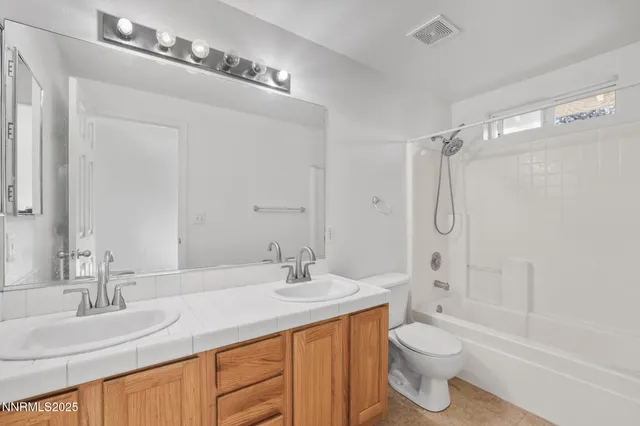 a bathroom with a granite countertop sink a toilet and shower