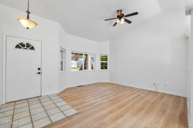 a view of an empty room and chandelier fan
