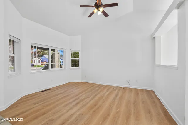 a view of empty room with wooden floor and fan