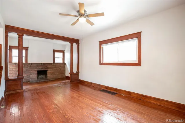 a view of an empty room with wooden floor fireplace and a window
