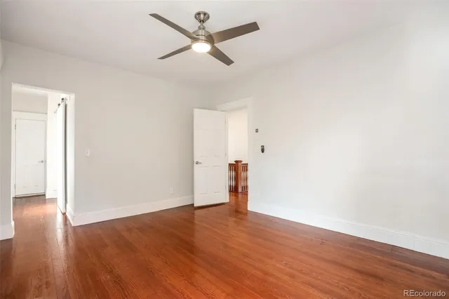 an empty room with wooden floor and a ceiling fan
