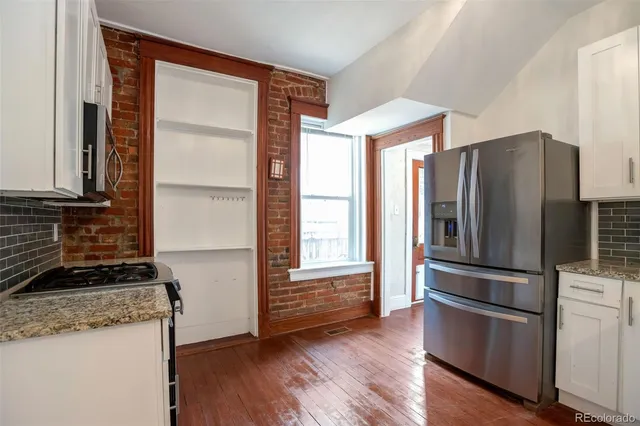 a kitchen with granite countertop stainless steel appliances a refrigerator and a stove top oven