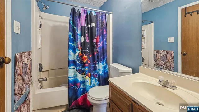 a white toilet sitting next to a bathroom sink and a shower curtain