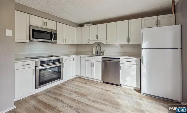 a kitchen with white cabinets and stainless steel appliances