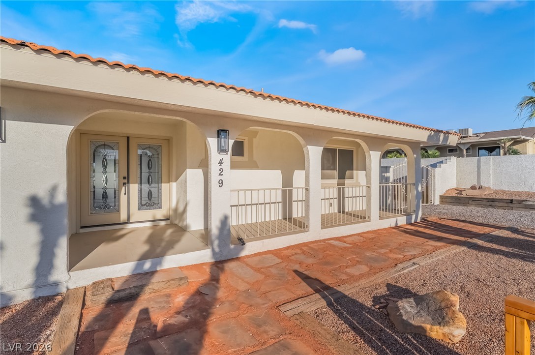 429 Crestway Road Henderson, NV 89015 - Photo 8 of 56 A terracotta-tiled roof crowns this stucco-finished home, featuring an arched entryway and a gravel front yard with stepping stones.