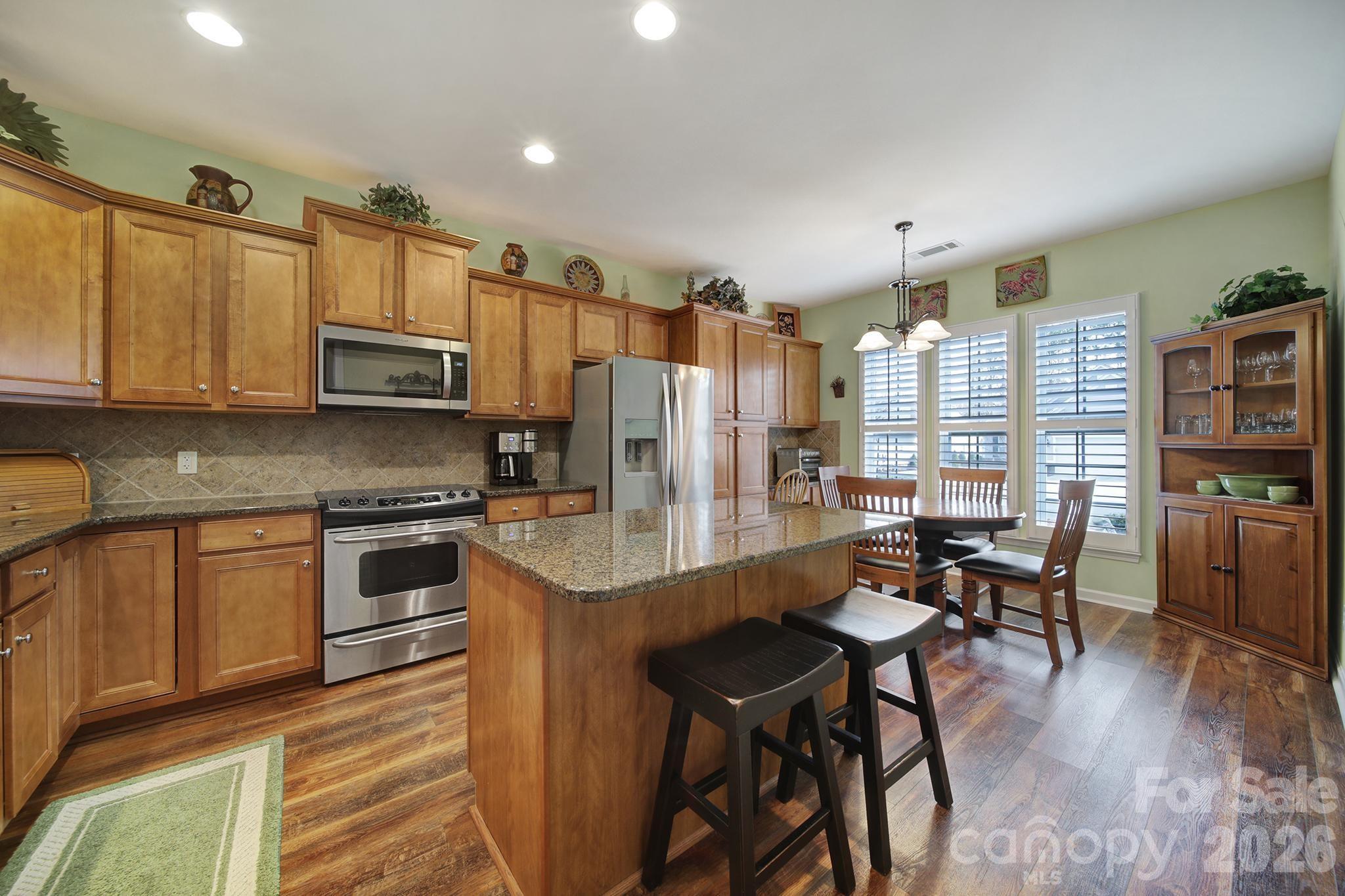 52083 Longspur Lane Fort Mill, SC 29707 - Photo 4 of 48 a kitchen with stainless steel appliances granite countertop a stove top oven a sink a refrigerator white cabinets and wooden floor