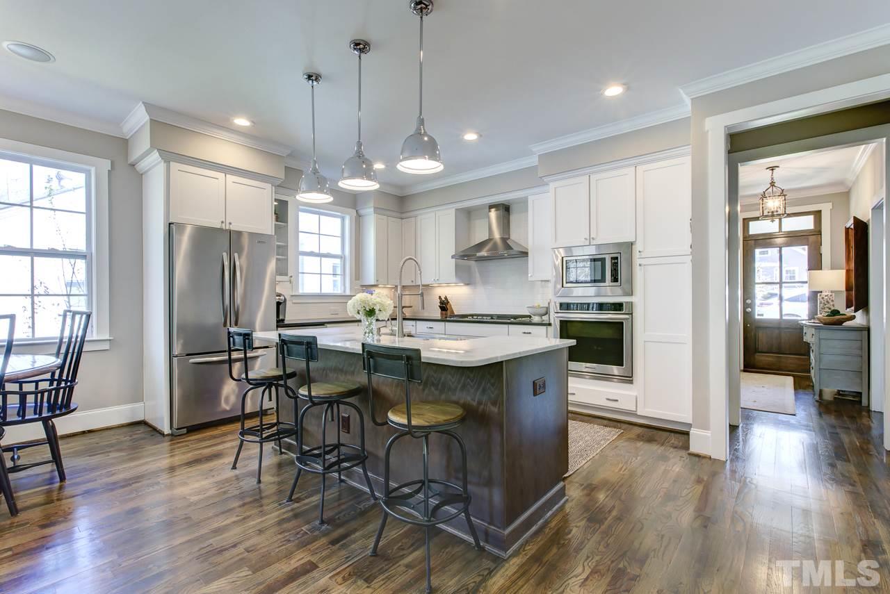 1711 Center Road Raleigh, NC 27608 - Photo 5 of 25 a kitchen with stainless steel appliances granite countertop a dining table chairs refrigerator and wooden floor