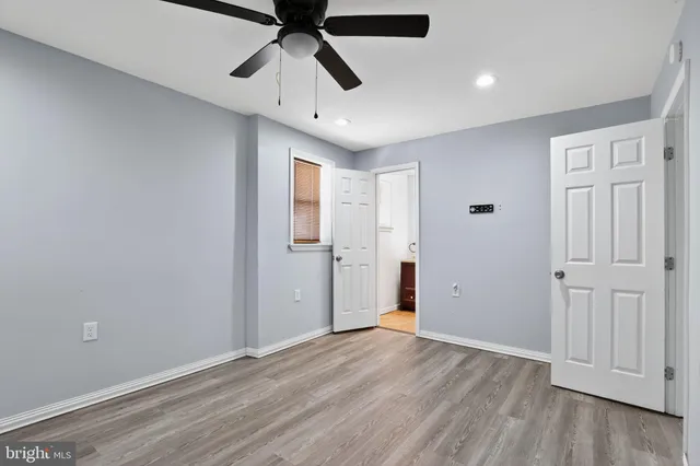 an empty room with wooden floor ceiling fan and windows