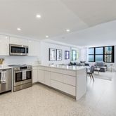 a large white kitchen with white cabinets and stainless steel appliances